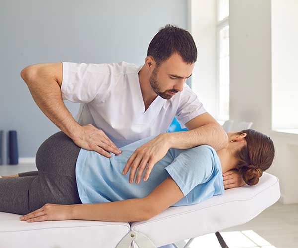 Chiropractor treating a young woman on a medical couch