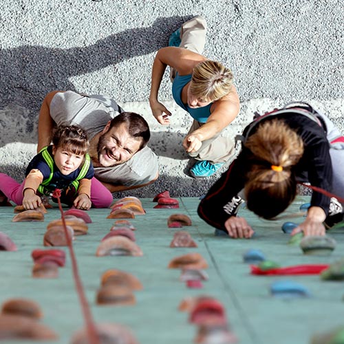 Family receiving instruction how to use a climbing wall