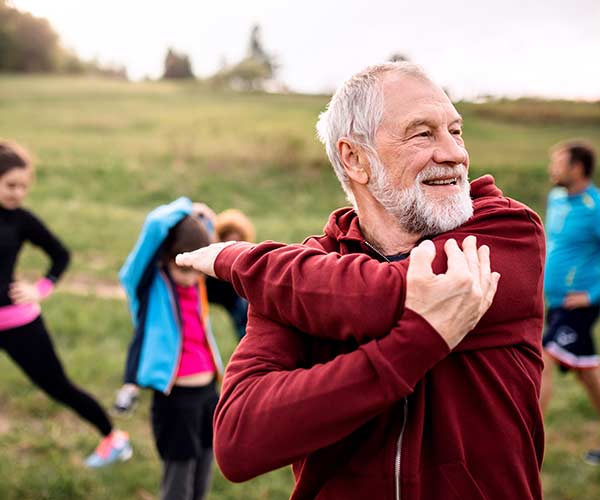 Mature man stretching in outdoor exercise class